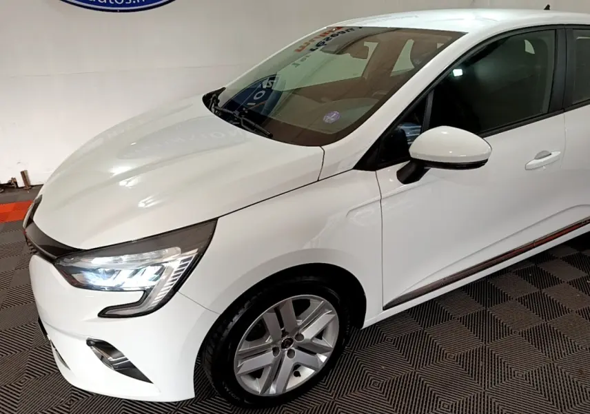 Renault Clio Business TCe 100 blanc vue 3/4 avant droit avec phares LED allumés et jantes alliage.