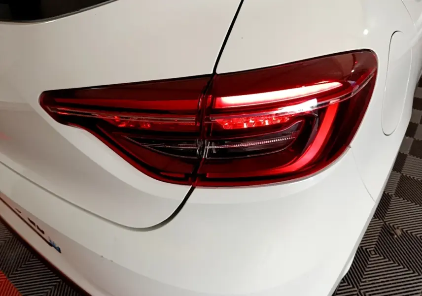 Feu arrière droit allumé d'une Renault Clio Business TCe 100 blanche, vue rapprochée sur l'arrière du véhicule.