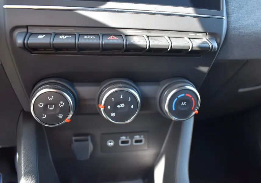 Gros plan sur les commandes de climatisation et boutons de fonction du tableau de bord de la Renault Clio V noire 2025.