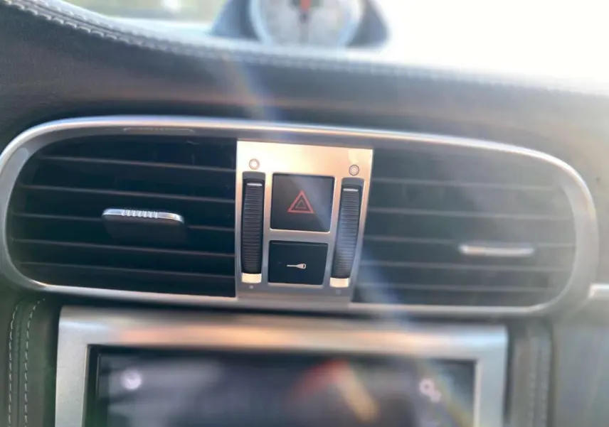 Gros plan sur la console centrale de la Porsche 911 997 Carrera 4S 2007, montrant les aérateurs et commandes d'alerte.