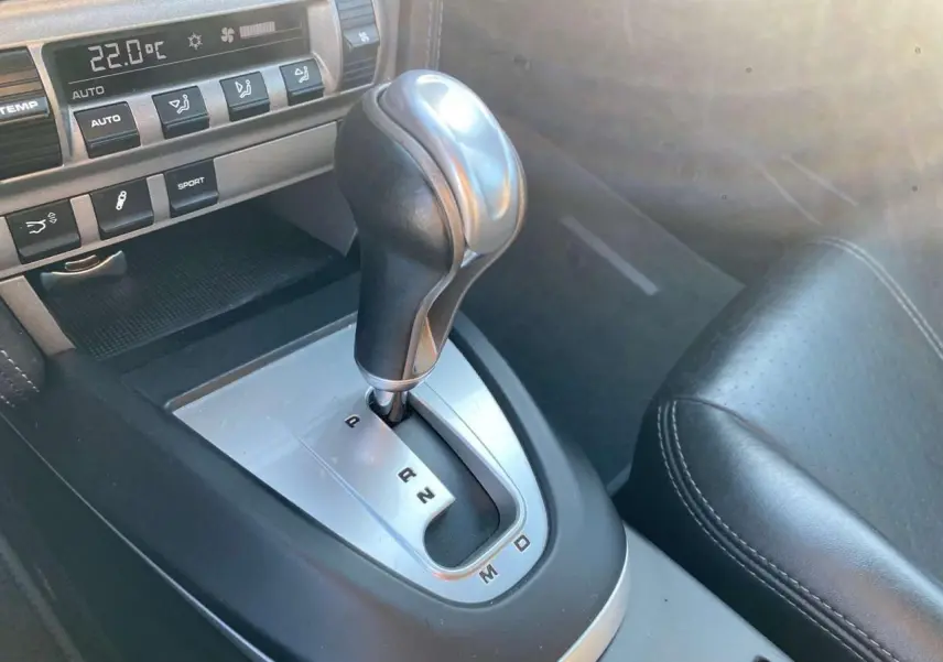 Gros plan sur la commande de boîte automatique Tiptronic en cuir et aluminium dans l'habitacle noir d'une Porsche 911 Carrera 4S 2007.