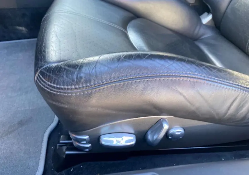 Gros plan sur le siège avant en cuir noir de la Porsche 911 997 Carrera 4S, montrant les commandes électriques latérales.