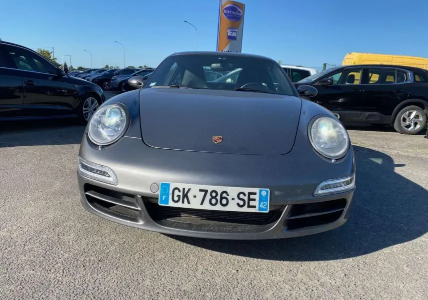 Vue avant d'une Porsche 911 Carrera 4S gris météore stationnée en extérieur sous un ciel bleu.