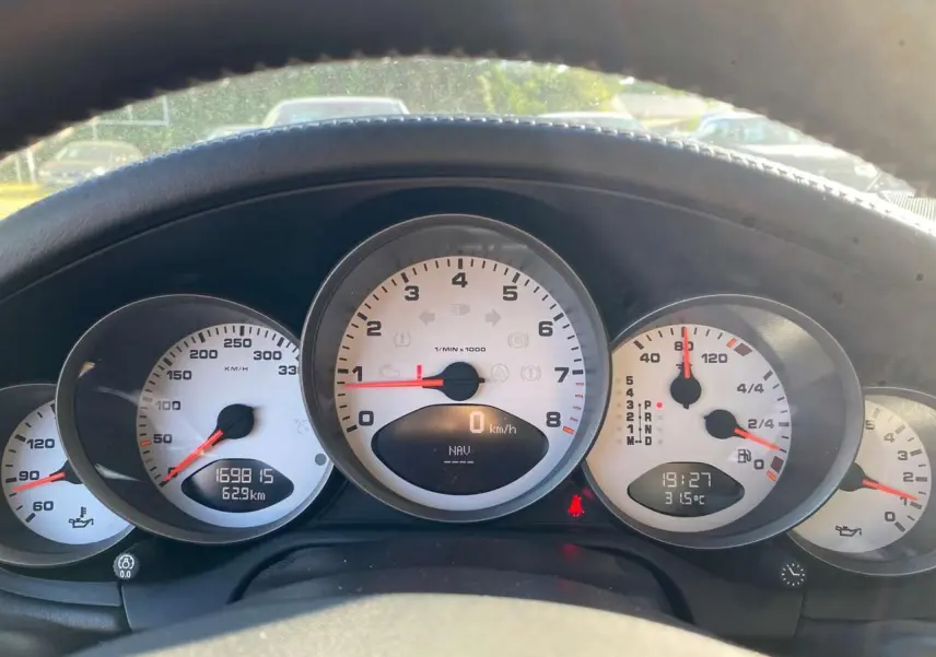Vue rapprochée du tableau de bord blanc de la Porsche 911 997 Carrera 4S gris météore, avec compte-tours central et affichages numériques.