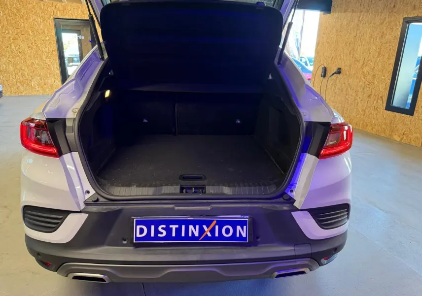 Vue arrière d'un Renault Arkana blanc nacré avec coffre ouvert et sorties d'échappement chromées visibles en intérieur.