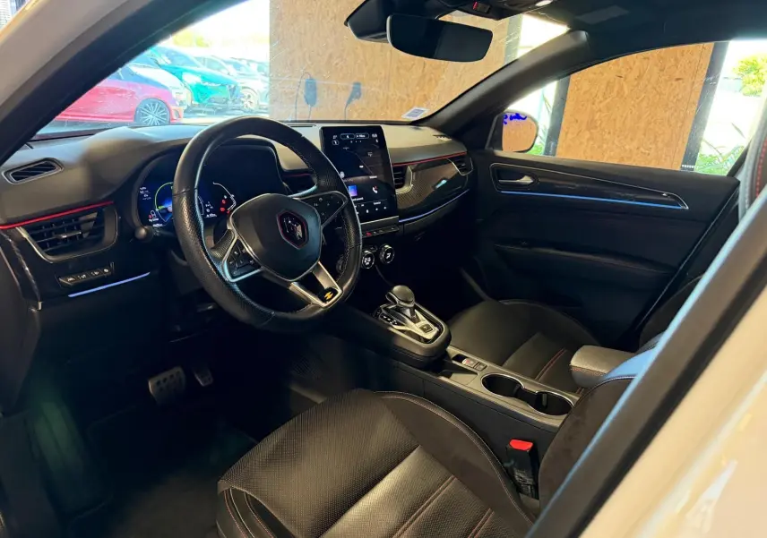 Vue intérieure côté conducteur de la Renault Arkana blanc nacré, volant cuir multifonctions et écran tactile vertical.
