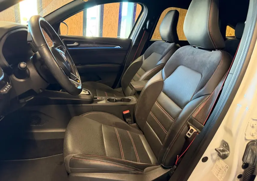 Vue intérieure côté conducteur du Renault Arkana blanc nacré, sièges sport noir avec surpiqûres rouges et volant cuir multifonctions.