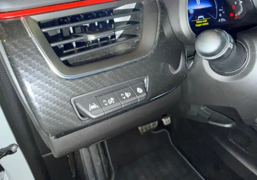 Vue intérieure côté conducteur du tableau de bord noir avec commandes d’aides à la conduite et ventilation sur Renault Arkana blanc nacré.