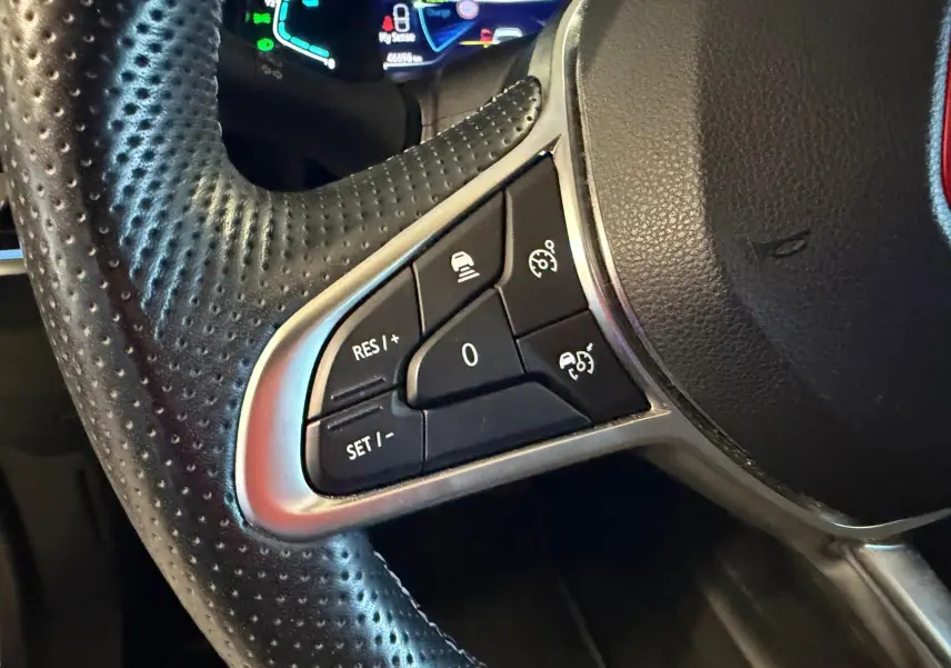 Gros plan sur les commandes multifonctions à gauche du volant cuir perforé du Renault Arkana blanc nacré.