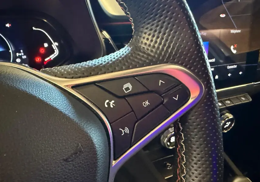 Gros plan sur le volant cuir perforé côté gauche du Renault Arkana blanc nacré avec commandes multifonctions visibles.