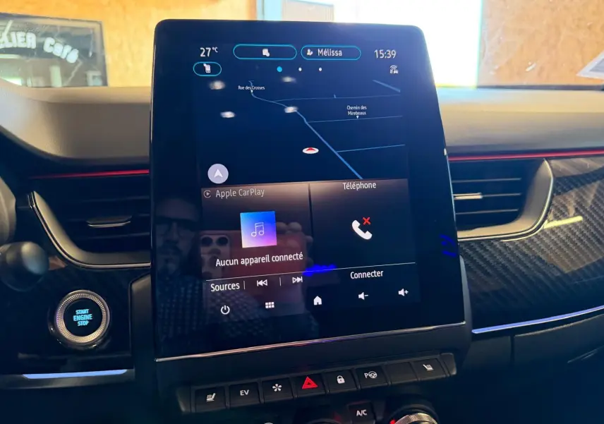 Vue rapprochée de l’écran tactile central du Renault Arkana blanc nacré 2021 avec commandes climatisation et démarrage.
