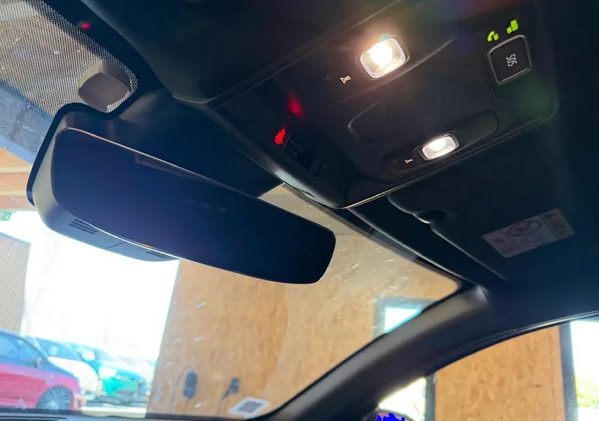 Vue intérieure du rétroviseur central et plafonnier avec éclairage allumé dans un Renault Arkana blanc nacré.