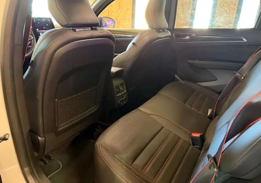 Vue intérieure arrière côté droit du Renault Arkana blanc nacré, sièges cuir noir avec surpiqûres rouges et console centrale.