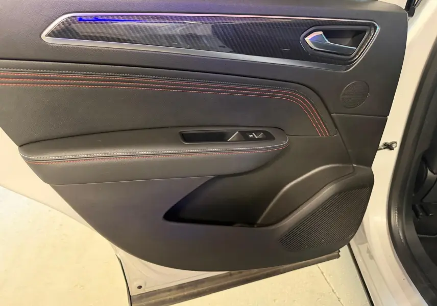 Vue intérieure côté gauche de la porte avant blanche nacrée du Renault Arkana avec surpiqûres rouges et insert carbone.