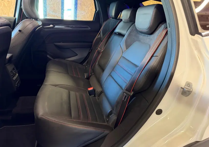 Vue intérieure côté gauche des sièges arrière noirs en cuir et suédine avec surpiqûres rouges d'un Renault Arkana blanc nacré.