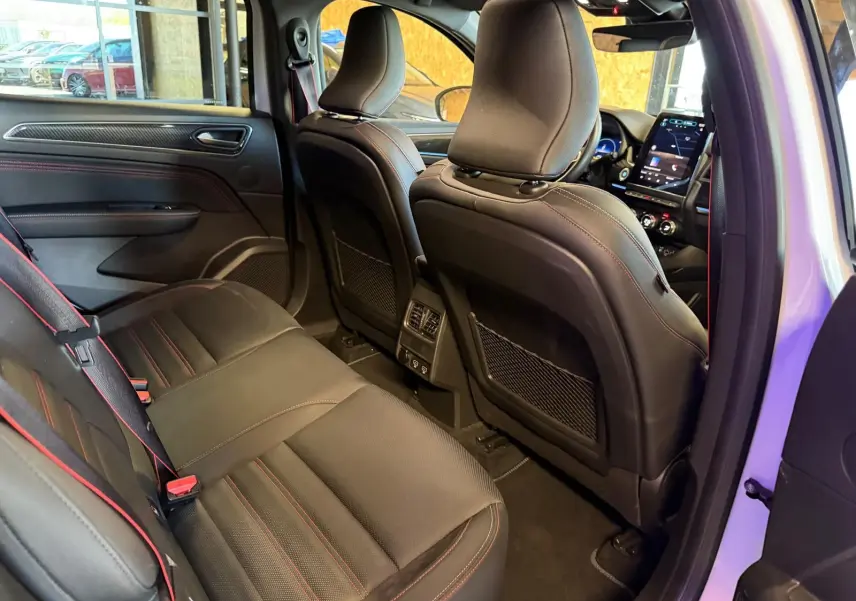 Vue intérieure arrière côté droit du Renault Arkana blanc nacré, sièges sport noirs avec surpiqûres rouges et écran tactile visible.