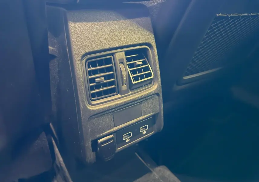 Détail des aérateurs arrière et ports USB dans l'habitacle sombre d'une Renault Arkana blanc nacré.