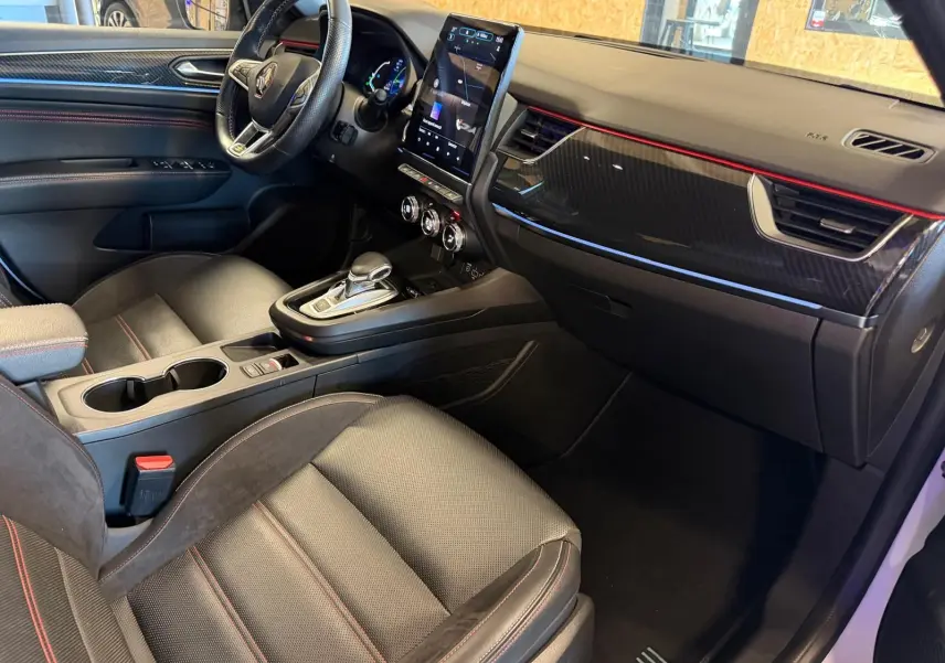Vue intérieure côté passager du Renault Arkana 1.6 E-Tech hybrid 145 RS Line avec sièges sport noirs et écran tactile vertical.