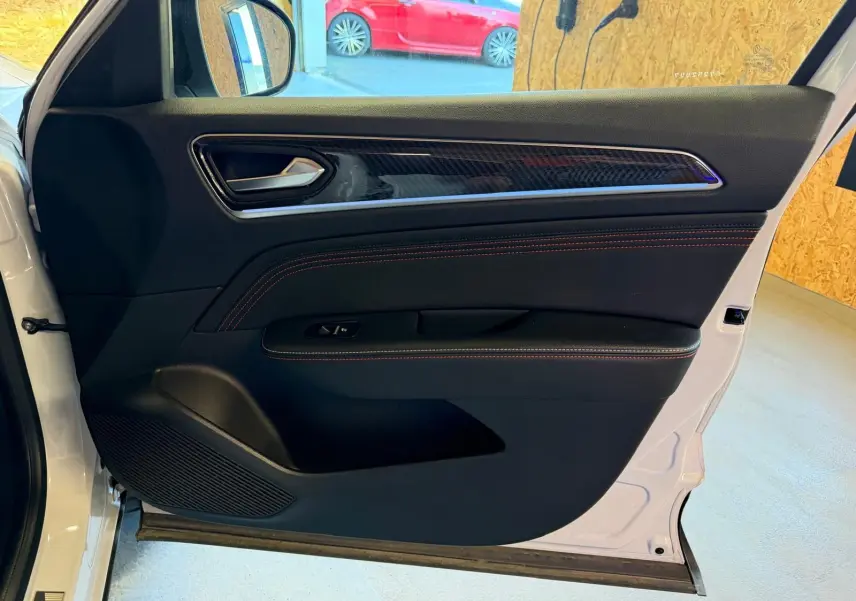 Vue intérieure de la porte avant gauche blanche nacrée du Renault Arkana 1.6 E-Tech hybrid 145 RS LINE avec surpiqûres rouges.