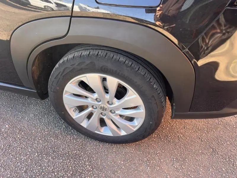 Gros plan sur la roue arrière droite du Suzuki S-Cross Cosmic Black Pearl avec jante alu et passage de roue noir mat.