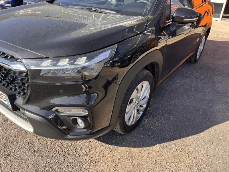 Vue 3/4 avant droit du Suzuki S-Cross 2024 noir Cosmic Black Pearl avec phares LED et jantes alu visibles.