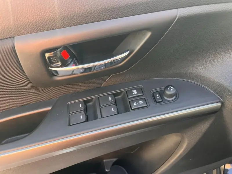Vue rapprochée de la porte avant gauche du Suzuki S-Cross 2024 avec commandes de vitres et poignée chrome.