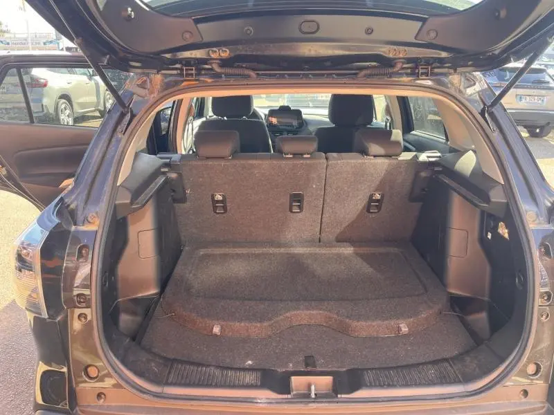 Vue arrière ouverte du coffre spacieux du Suzuki S-Cross 2024 en Cosmic Black Pearl métallisé, banquette arrière relevée.