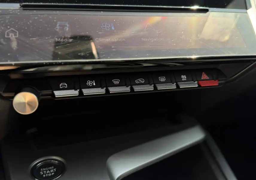 Gros plan sur la console centrale de la Peugeot 308 Hybrid 2025, boutons de commande et écran tactile visibles.