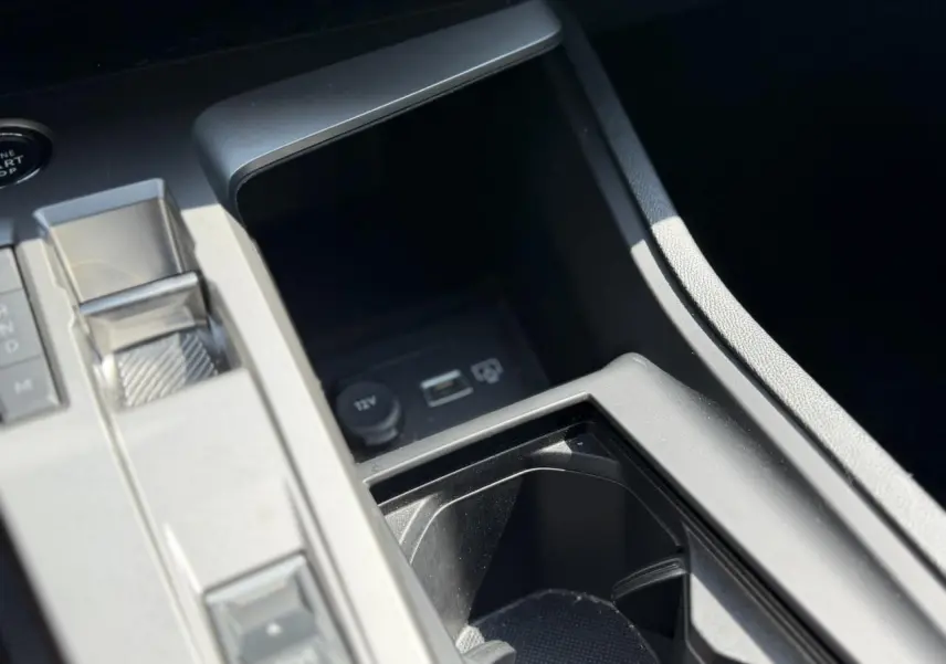 Gros plan sur la console centrale noire du Peugeot 308 Hybrid 145 e-DSC6 Allure avec chargeur induction et bouton start.