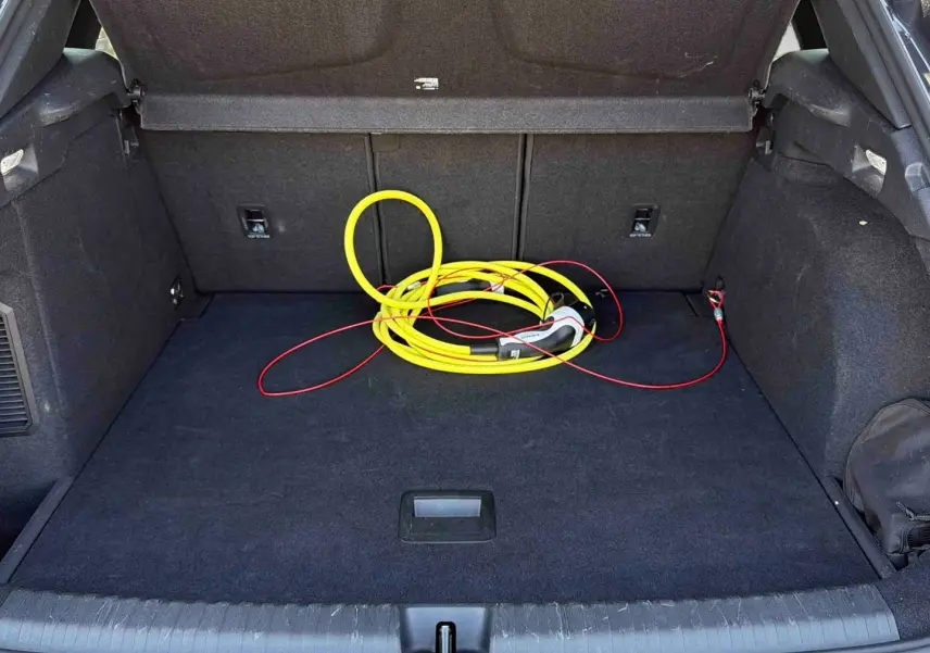 Coffre ouvert d'une CUPRA Terramar gris, vue intérieure montrant un câble de recharge jaune enroulé.