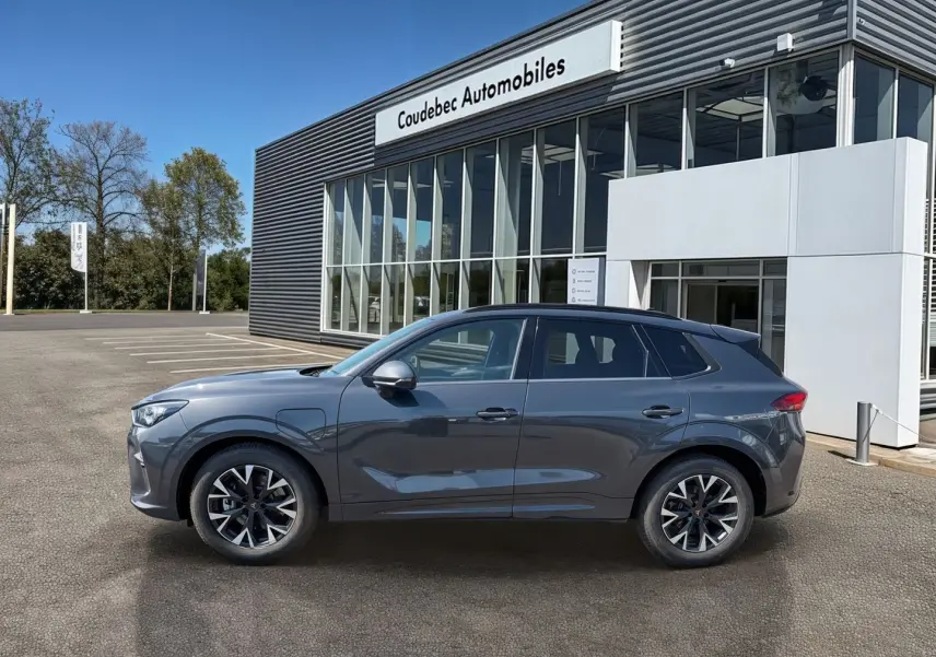 Vue de profil côté gauche d'un CUPRA TERRAMAR gris 2025 garé devant un bâtiment vitré de concession.