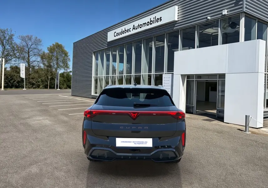 Vue arrière d'une CUPRA Terramar grise 2025 stationnée devant un bâtiment moderne de concession.