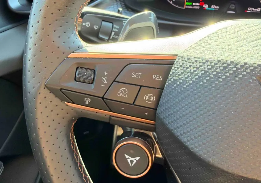 Gros plan sur le volant cuir perforé gris du CUPRA TERRAMAR avec commandes multifonctions et logo orange distinctif.