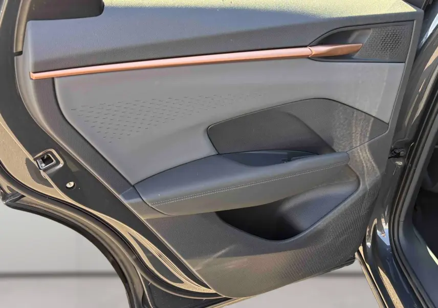 Vue rapprochée de la porte arrière gauche grise du CUPRA TERRAMAR 2025 avec insert décoratif cuivre et habillage tissu et cuir.