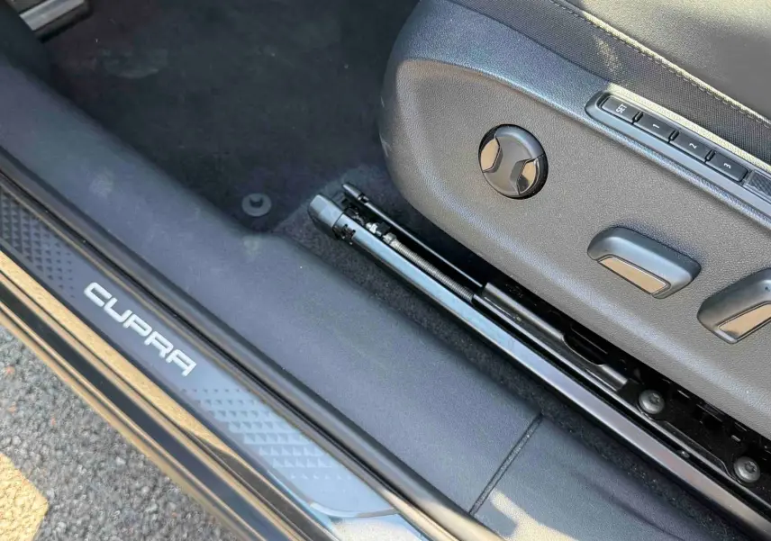 Gros plan sur le réglage électrique du siège avant droit et la plaque de seuil de porte CUPRA gris foncé.