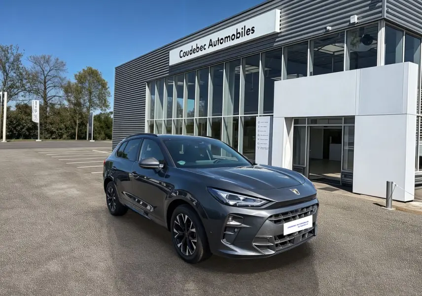 CUPRA TERRAMAR gris en 3/4 avant droit, avec jantes 18'' anthracites et calandre imposante devant un concessionnaire.