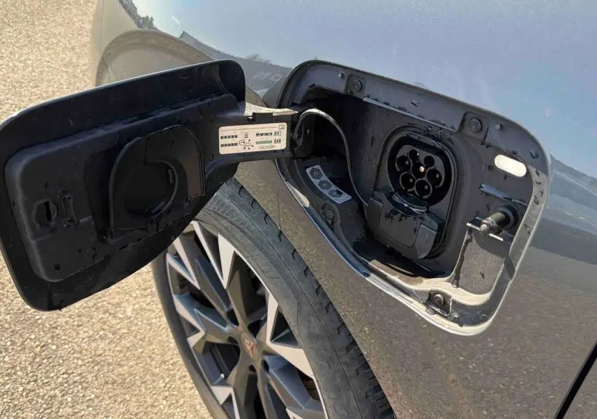Prise de recharge ouverte côté gauche sur CUPRA TERRAMAR gris, avec jante 18 pouces anthracite visible.