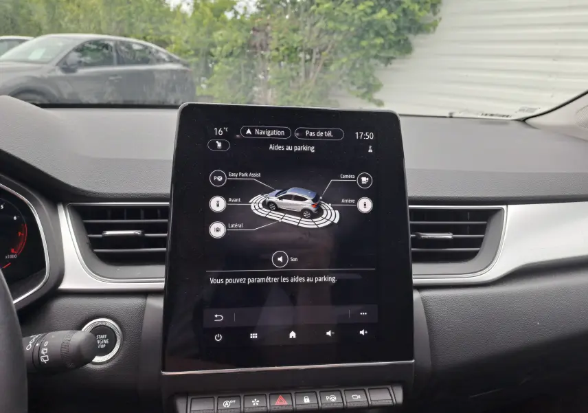 Écran tactile central du tableau de bord du Renault Captur 2024 affichant les aides au parking en intérieur.