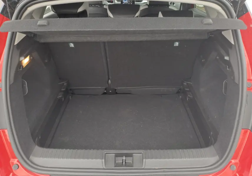 Coffre ouvert vu de l'arrière d'un Renault Captur rouge flamme métal, montrant l'espace de chargement vide et la tablette cache-bagages.