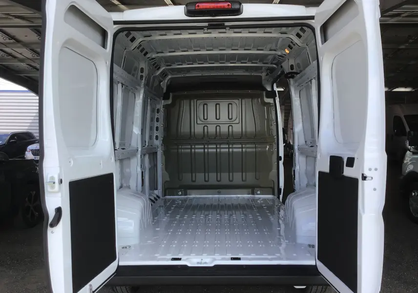 Vue arrière du Peugeot Boxer Fourgon blanc 2025 avec portes ouvertes montrant l'espace de chargement vide et métallique.