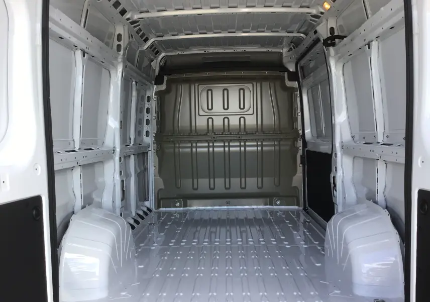 Intérieur vide du fourgon Peugeot Boxer blanc, vue depuis l'arrière vers la cloison métallique avant.
