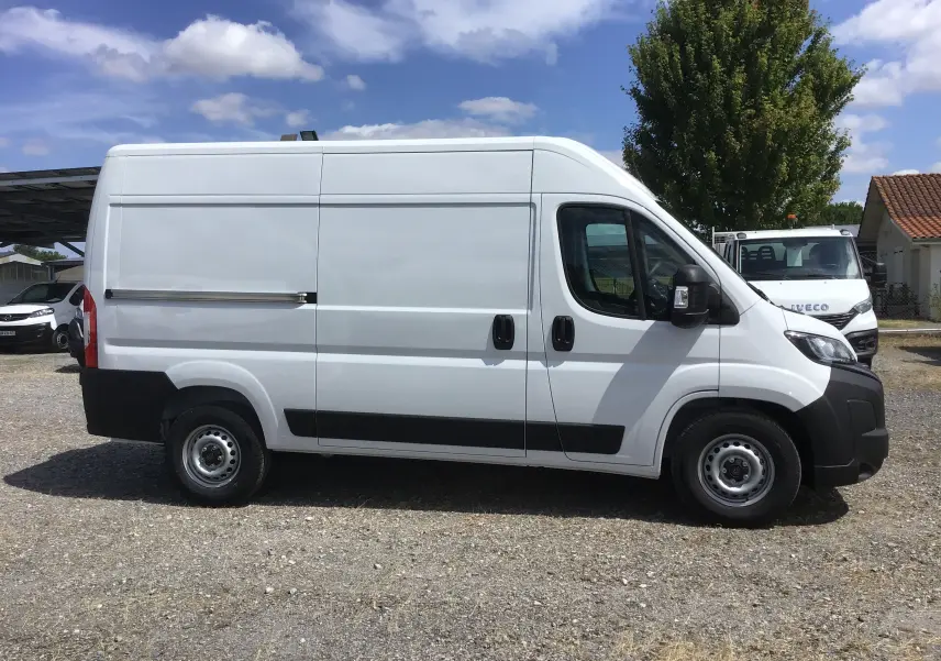 Profil droit d’un utilitaire Peugeot Boxer blanc L2H2 2025 avec portes latérales coulissantes et protections noires.