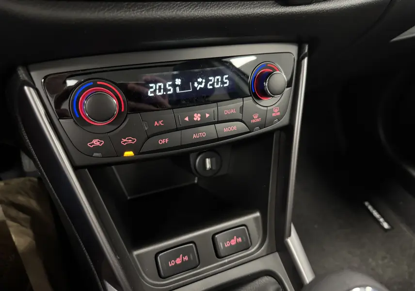 Gros plan sur la console centrale du Suzuki S-Cross 2025, montrant la climatisation automatique et les commandes de sièges chauffants.