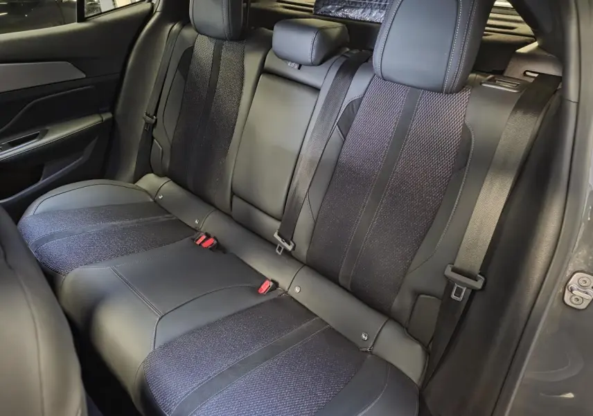Vue intérieure de la banquette arrière en tissu et cuir noir du Peugeot 408 gris, avec ceinture de sécurité et appuis-tête.