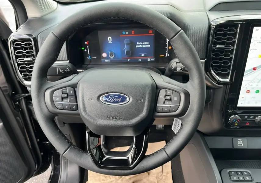 Vue intérieure centrée sur le volant cuir multifonctions du Ford Ranger noir Shadow avec tableau de bord digital et écran tactile.