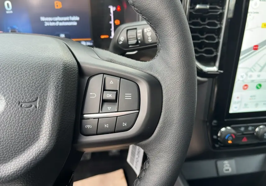 Gros plan sur le volant cuir multifonctions du Ford Ranger 2025 avec écran tactile et commandes au volant visibles.