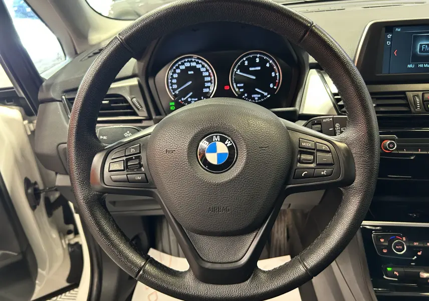 Vue intérieure centrée sur le volant noir de la BMW Série 2 Active Tourer 216d, tableau de bord et écran multimédia visibles.