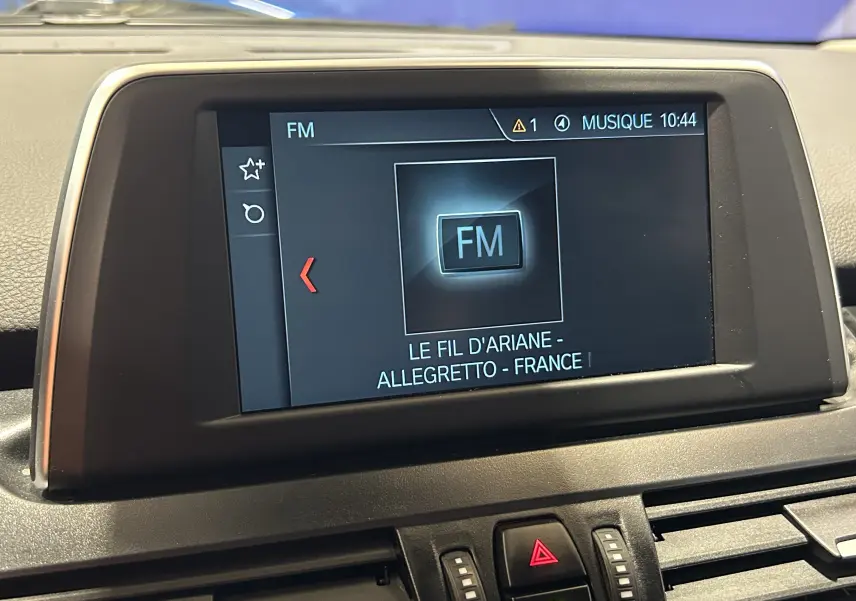 Écran central de la BMW Série 2 Active Tourer blanc, affichant la radio FM avec station Le Fil d'Ariane.