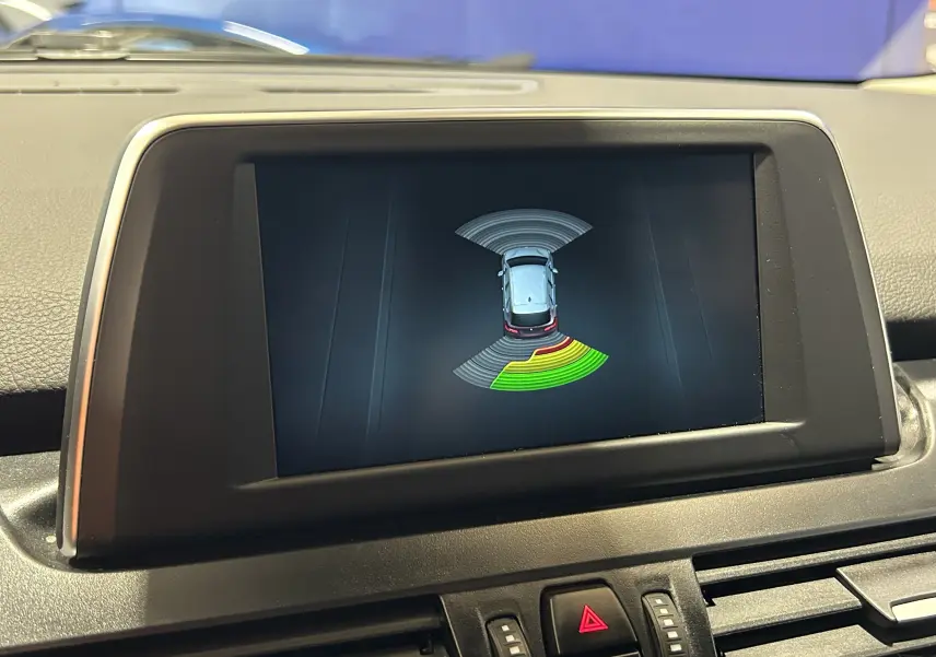Écran central montrant l'affichage des radars de recul du BMW Série 2 Active Tourer blanc, vue intérieure frontale.