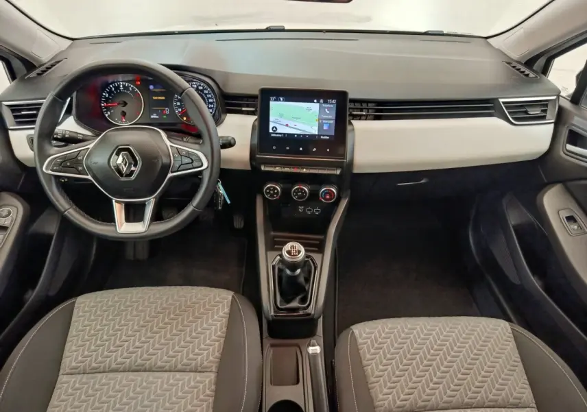 Vue intérieure avant de la Renault Clio blanche 2023, tableau de bord avec écran tactile central et volant multifonctions cuir.